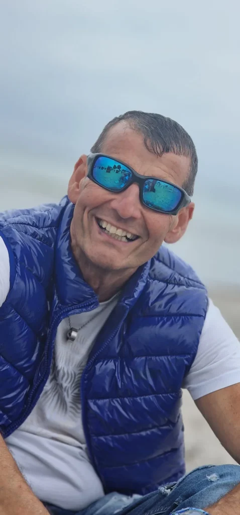 Klaus P. am Strand mit blauer Sonnenbrille